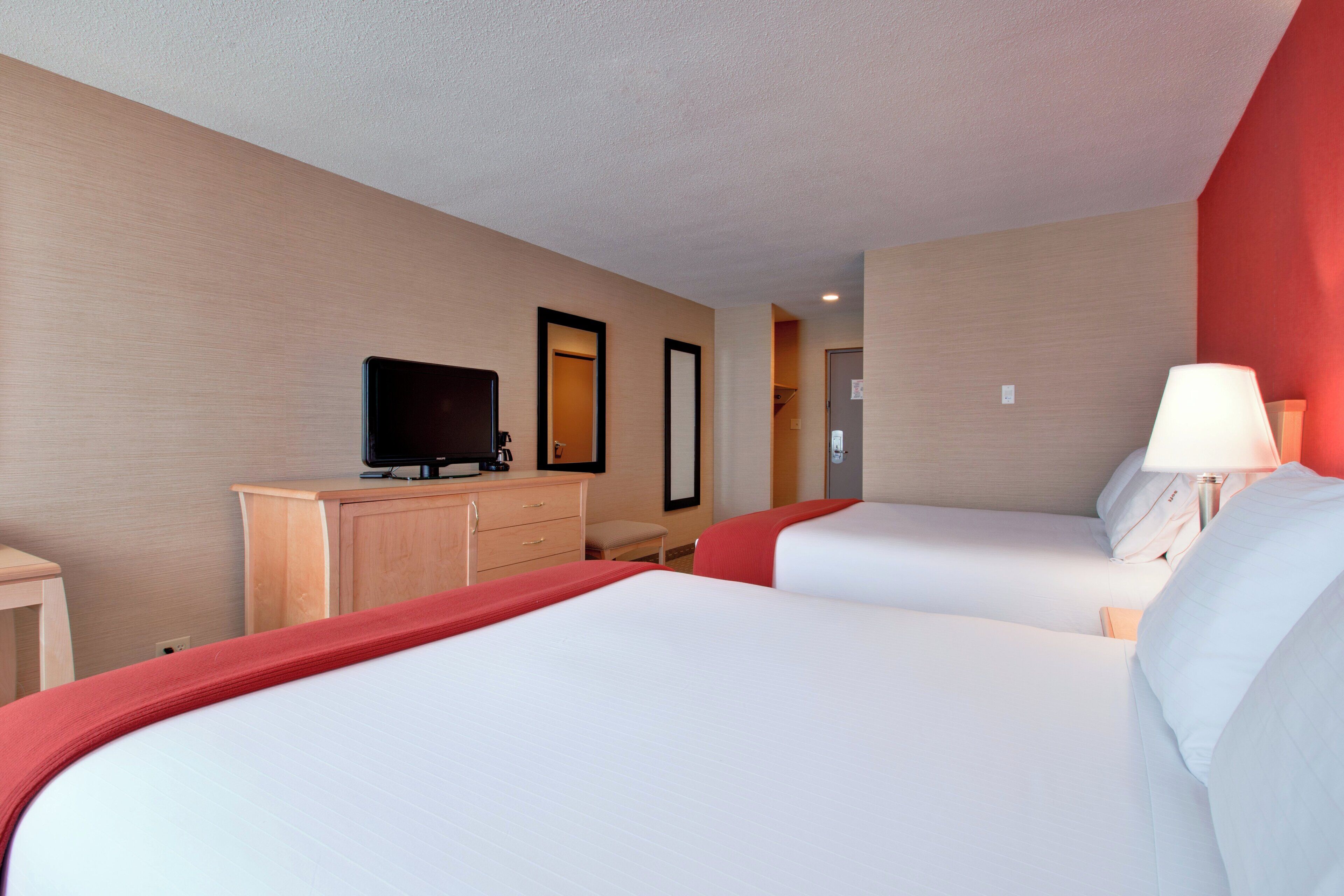 Une chambre d’hôtel avec deux lits, une télévision, un bureau et une lampe.
