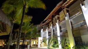 A multi-story hotel with a thatched roof, palm trees, and outdoor seating areas. - Laguna Beach Hotel & Spa (Grand River South East)
