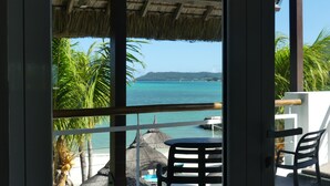 A balcony with a view of the sea, a thatched roof, and a table with chairs. - Laguna Beach Hotel & Spa (Grand River South East)