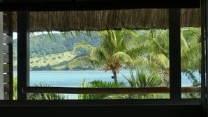 A room with a view of a tropical beach, palm trees, and a thatched roof. - Laguna Beach Hotel & Spa (Grand River South East)
