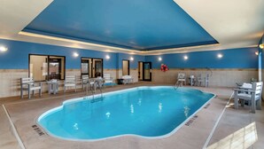 Piscina interior com faixas de separação bem definidas, cercada por espreguiçadeiras e mesas.