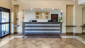 Uma receção com um letreiro a dizer "Comfort Inns & Suites", uma área de receção com balcão de mármore e um tapete de boas-vindas.