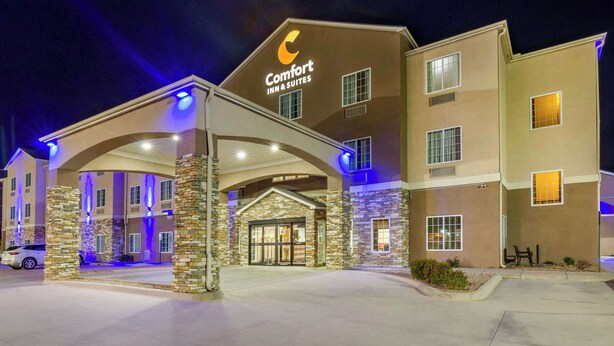 Edifício do Comfort Inn & Suites com fachada de pedra, várias janelas e entrada bem iluminada.
