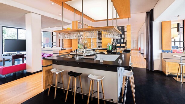 Een moderne keuken met een centraal eiland, barstoelen en hangende lampen.