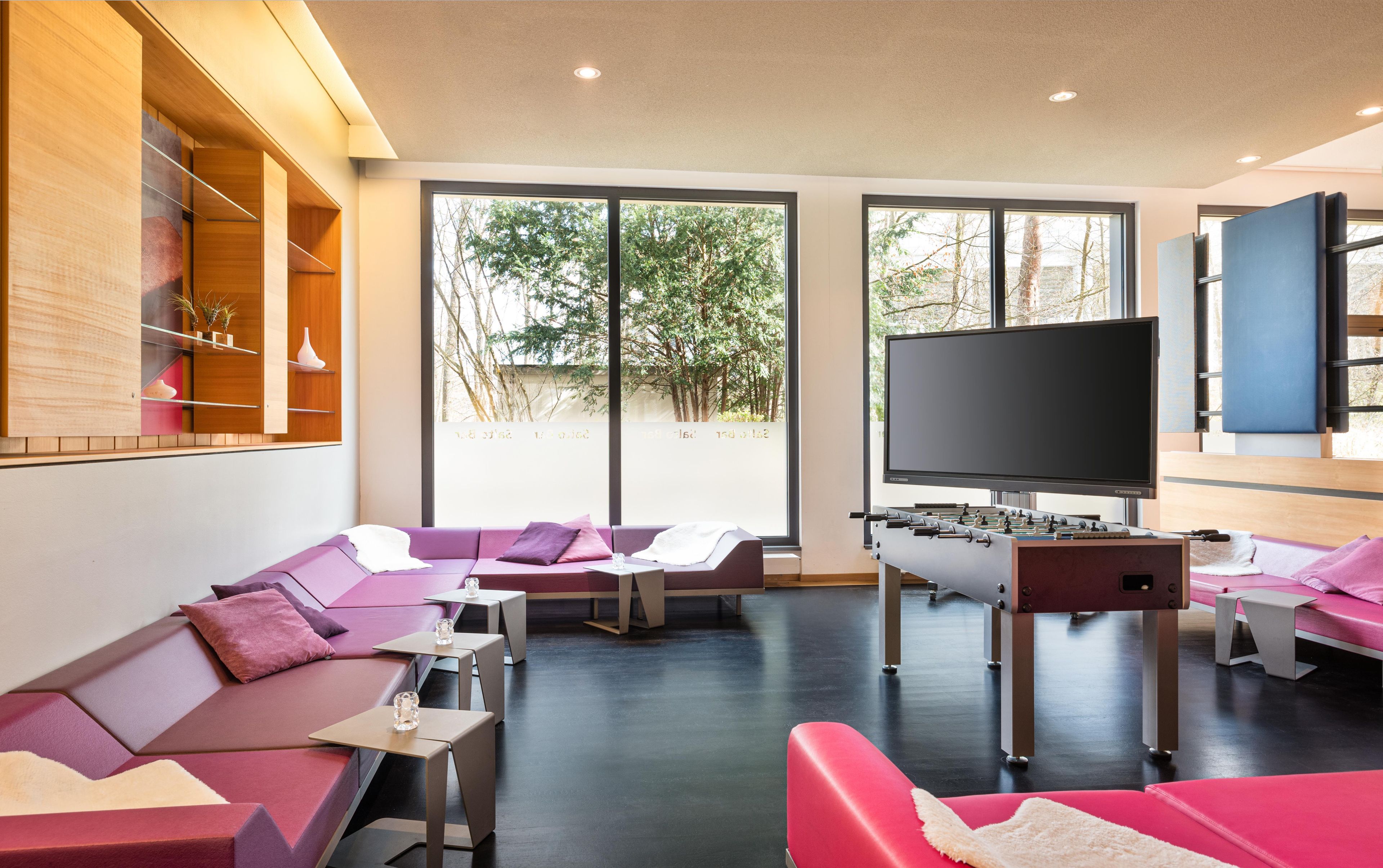 Ein modernes Wohnzimmer mit einer Sofagarnitur, einem Kicker und einem Fernseher.