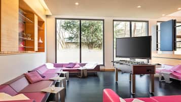 Ein modernes Wohnzimmer mit einer Sofagarnitur, einem Kicker und einem Fernseher.