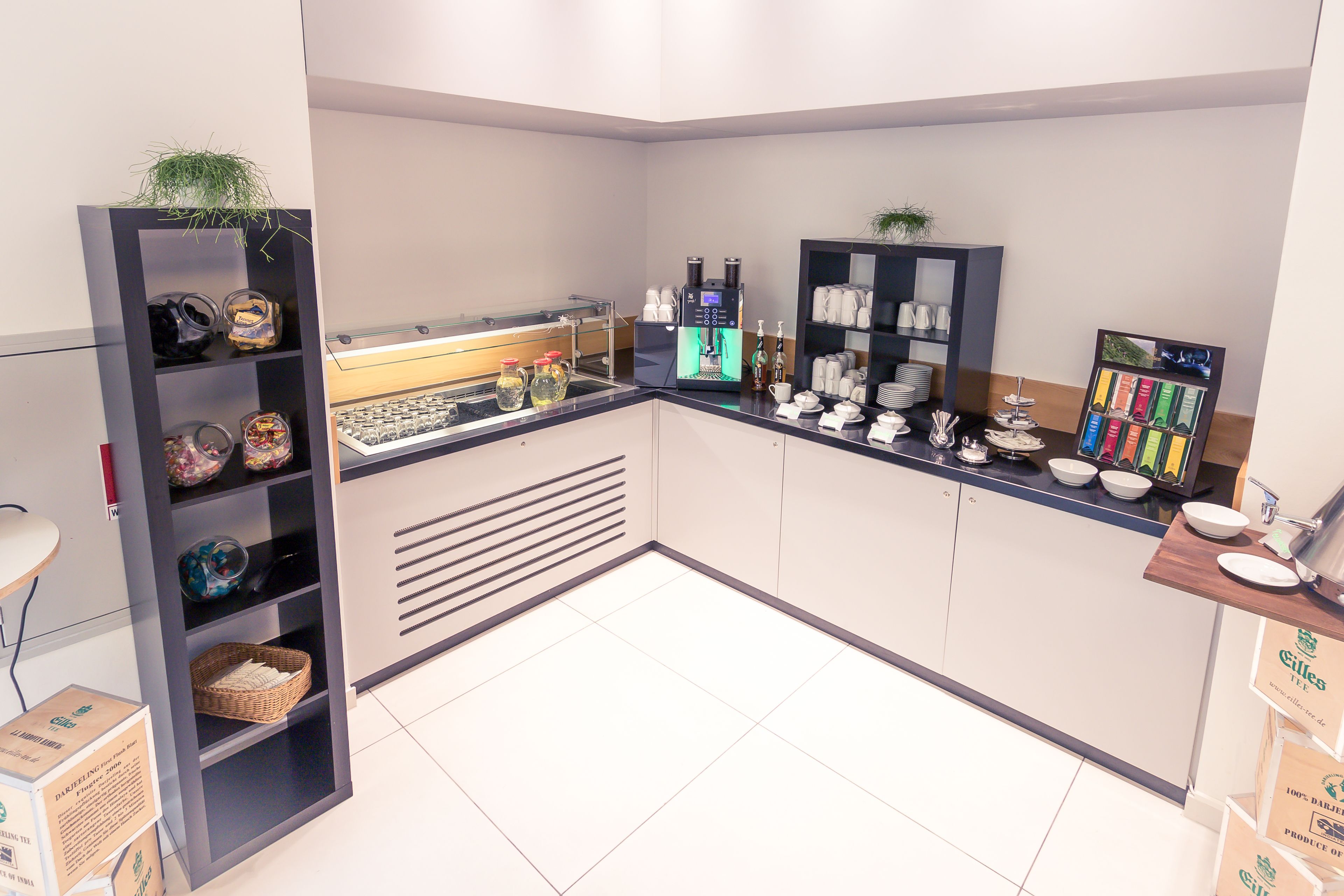 A modern kitchen with a coffee machine, shelves with kitchenware, and a display of coffee pods.