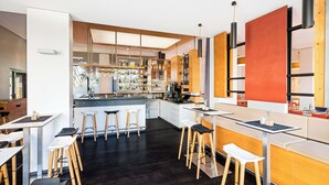 Een moderne bar met krukken, een toog en een divers assortiment flessen en glazen.