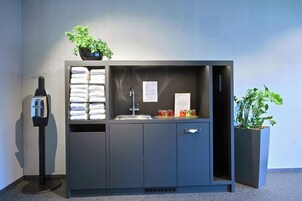 A modern bathroom with a sink, towel dispenser, and a potted plant.