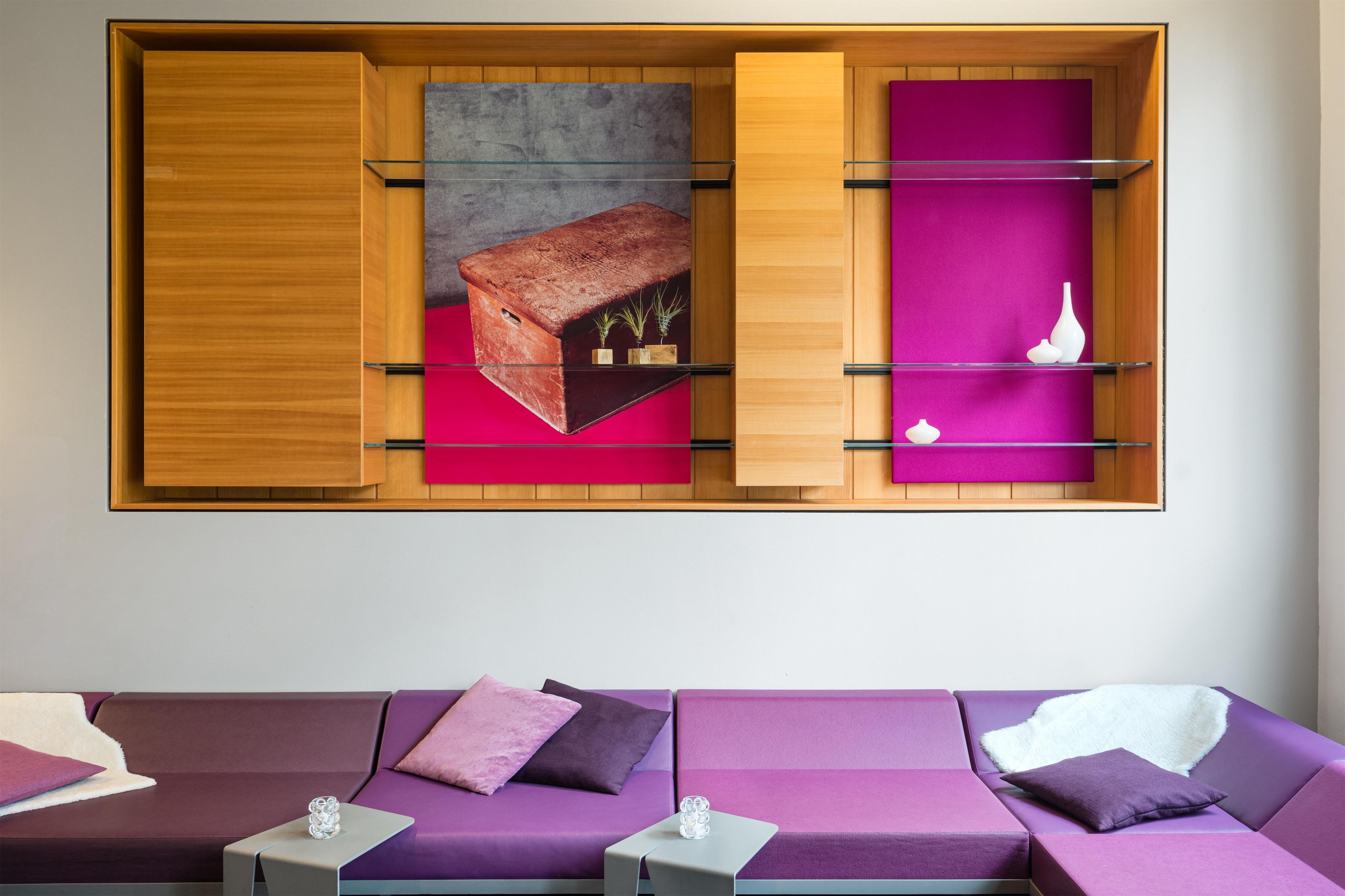 A modern interior with a wooden cabinet, a purple sofa, and a glass display case.