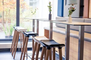 Un comedor moderno con una mesa de vidrio, sillas de madera y un florero con flores.