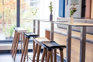 A modern dining area with a glass table, wooden chairs, and a vase with flowers.