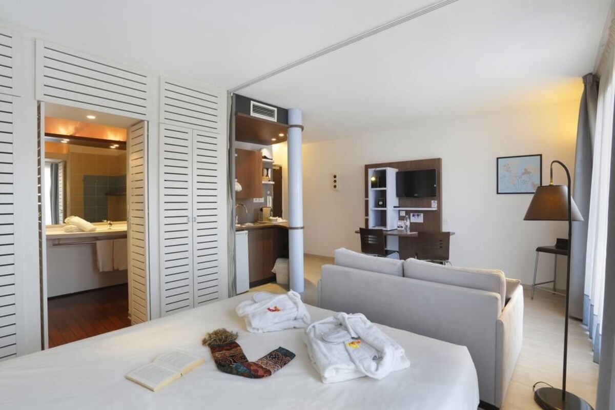 A hotel room with a bed, a sofa, a TV, and a desk with a chair.