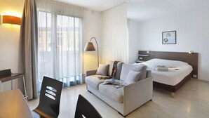 Una habitación de hotel moderna con sofá, cama, escritorio y silla.