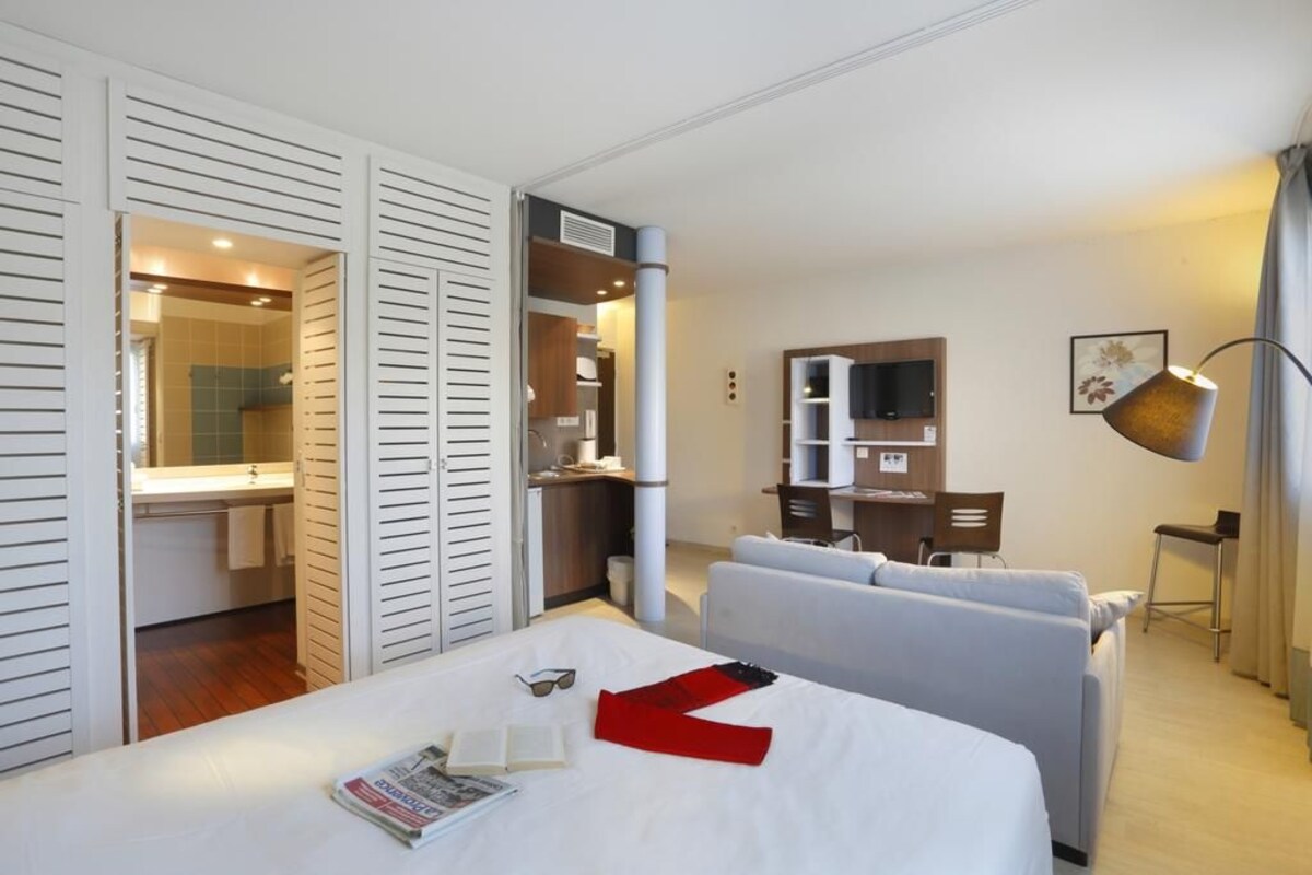 Una habitación de hotel con cama, escritorio, silla, televisor y armario.