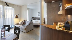 Una habitación de hotel moderna con comedor, cama y kitchenette.