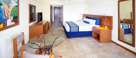 A hotel room with a bed, bedside table, lamp, and a glass table with chairs.