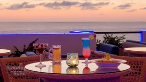 Una mesa con bebidas y un postre, con vista a la puesta de sol.