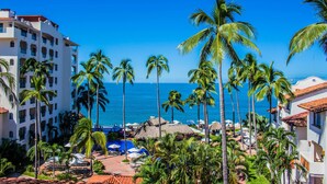 Un resort con zona de piscina, palmeras y vista al océano.