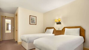 A hotel room with two beds, a door, a framed picture on the wall, and a wall-mounted lamp. - Days Inn by Wyndham Sevenoaks Clacket Lane (Westerham)