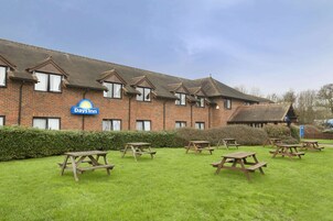 A Days Inn with a brick facade, multiple windows, and picnic tables in the front lawn.