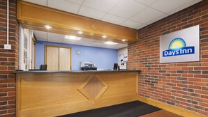 A reception desk with a Days Inn sign, a clock, and a coffee machine. - Days Inn by Wyndham Sevenoaks Clacket Lane (Westerham)