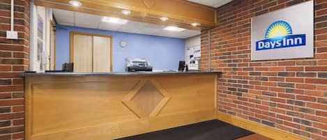 A reception desk with a Days Inn sign, a clock, and a coffee machine.