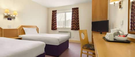 Habitación de hotel con dos camas, un escritorio con silla, televisión y ventana con cortinas.