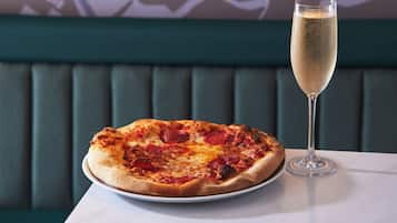 Una pizza en un plato y una copa de champán sobre una mesa.