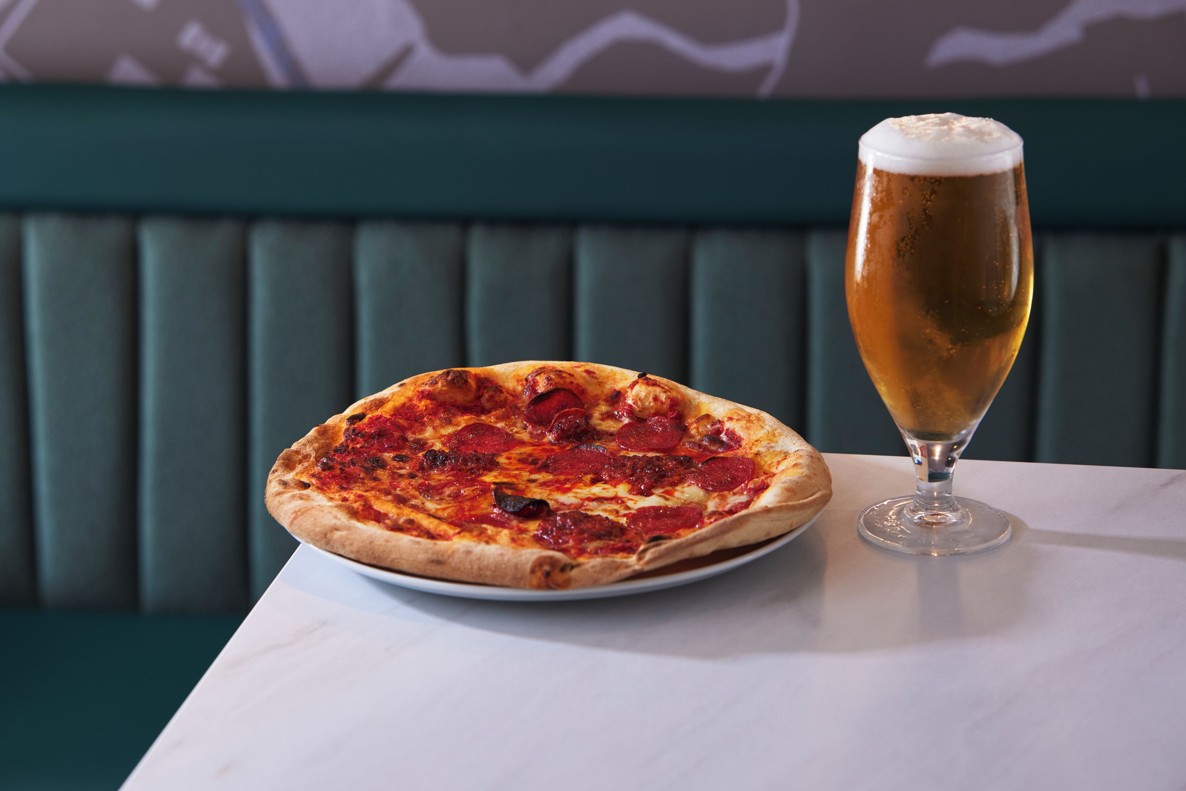 A pizza and a glass of beer on a table in a restaurant.