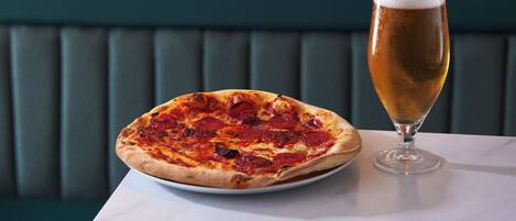 A pizza and a glass of beer on a table in a restaurant.
