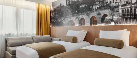 A hotel room with two beds, a large window with curtains, and a cityscape mural on the wall.