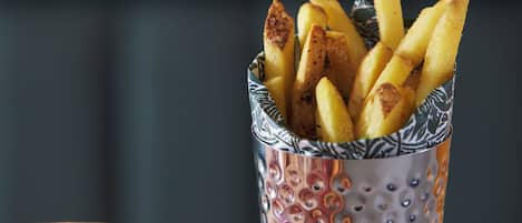 A basket of golden-brown fries next to a pizza with a red sauce.