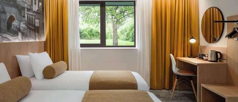 A hotel room with two beds, a desk, a chair, a large window with curtains, and a wall-mounted mirror.