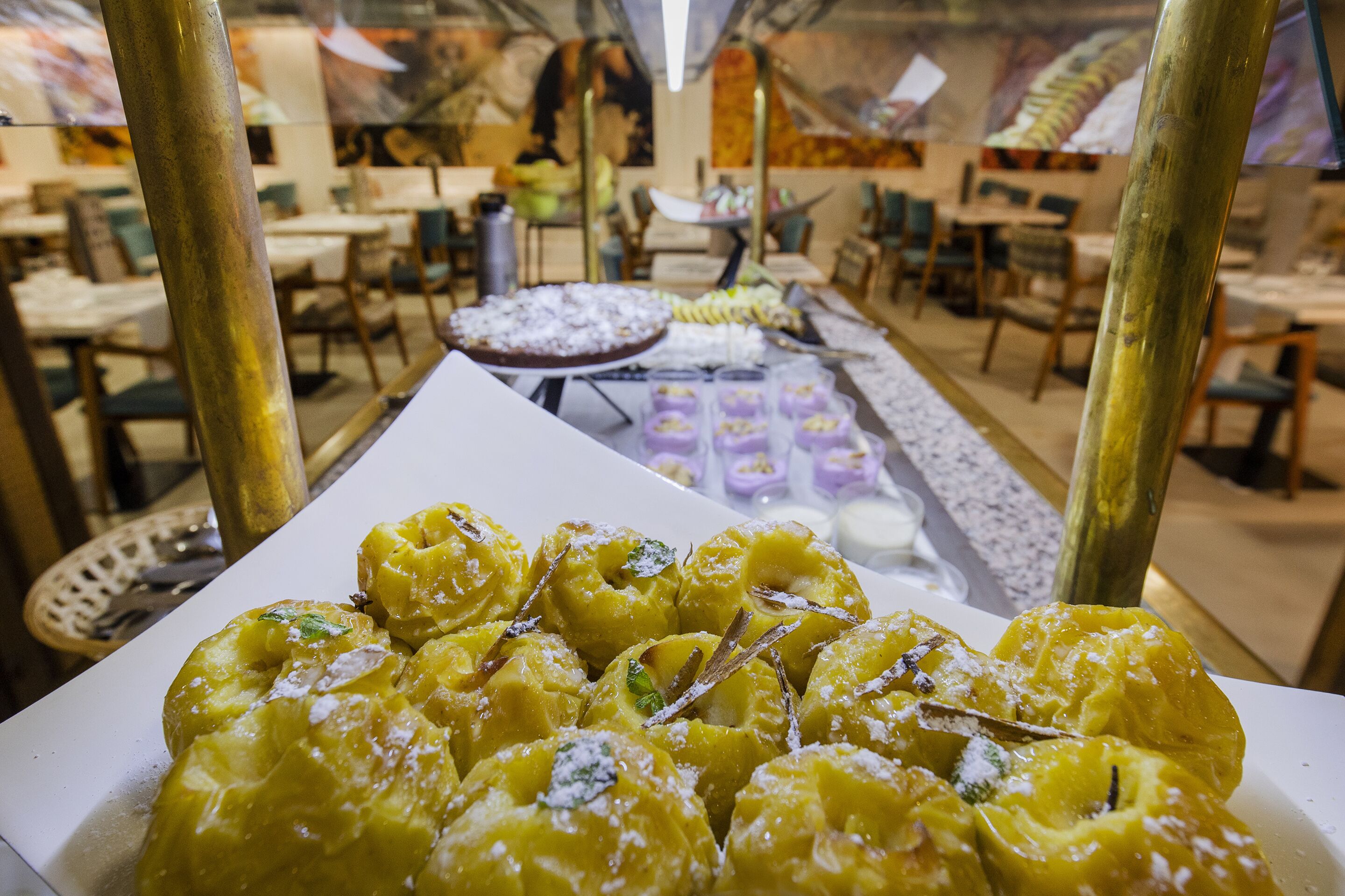 A buffet with various food items, including a large platter of yellow pastries and a dessert station with multiple small dishes.