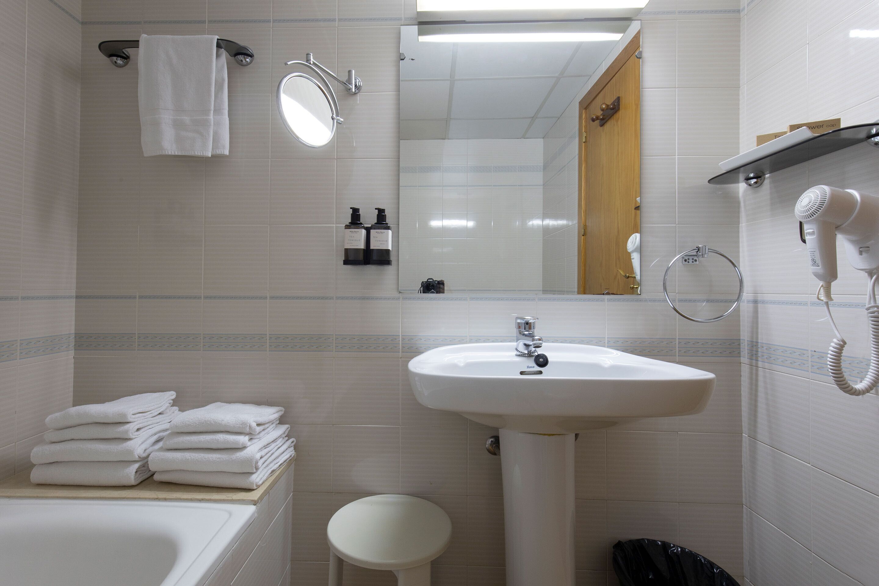 Ein Badezimmer mit Waschbecken, Spiegel, Handtuchhalter und Föhn.