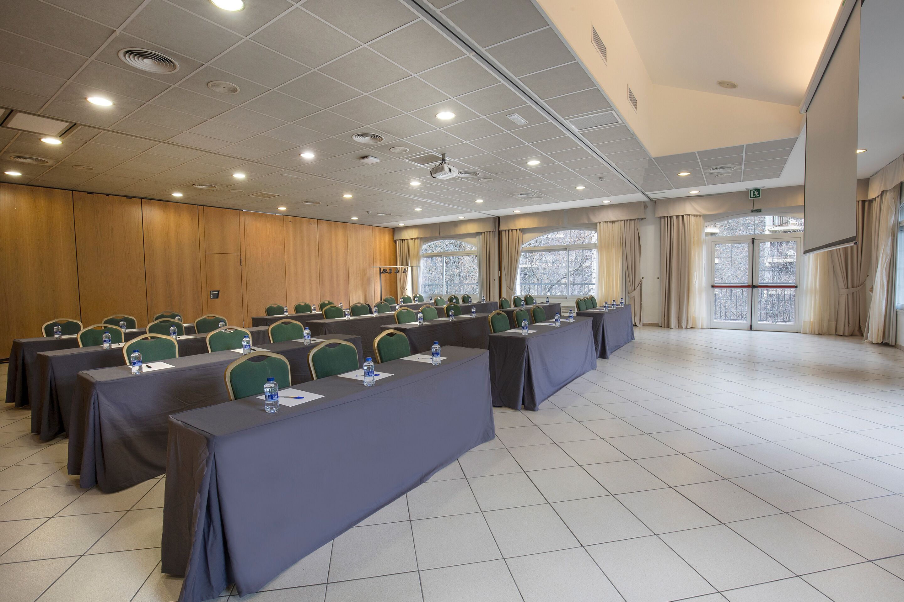 A conference room with rows of tables, chairs, and a projector screen.