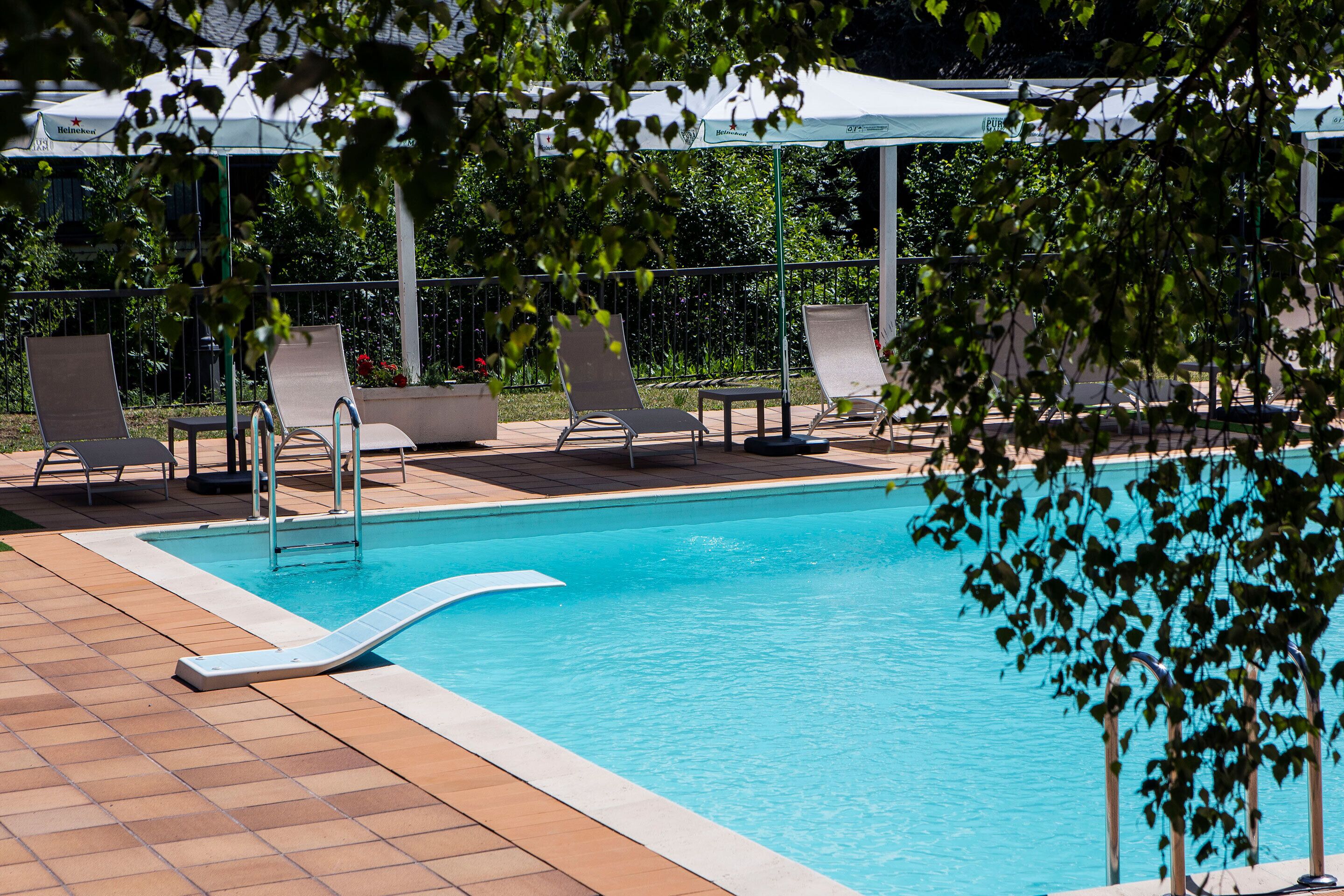 Una piscina con sillas de descanso y una zona cubierta.