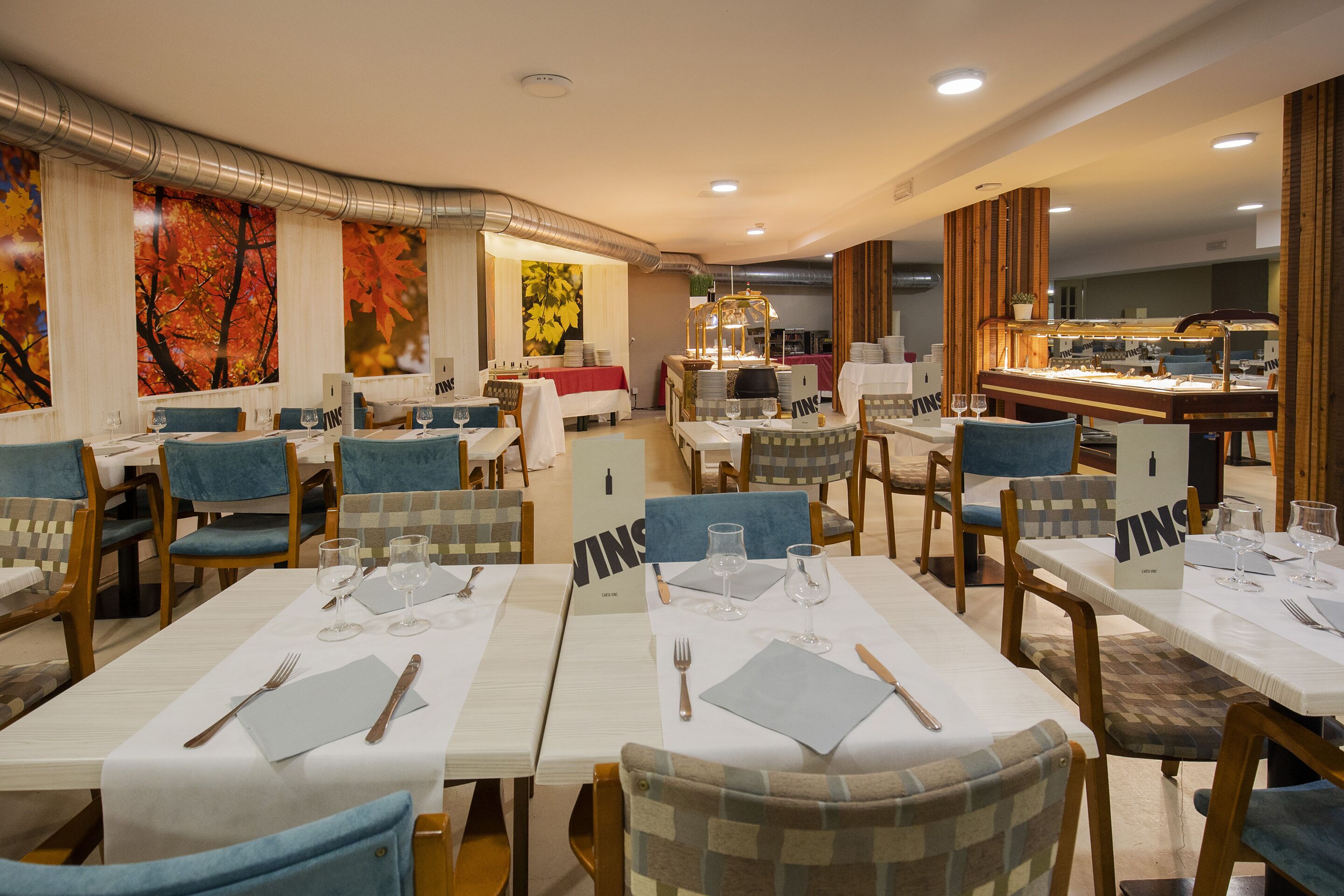 A restaurant with multiple tables set for dining, featuring a mix of blue and wooden chairs.