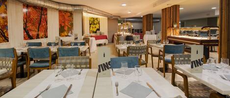 Un restaurante con varias mesas preparadas para comer, con una combinación de sillas azules y de madera.