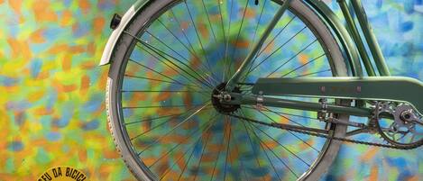 A vintage bicycle with a chain and seat, mounted on a wall with a colorful abstract background. A plaque with text and a logo is visible below the bicycle.
