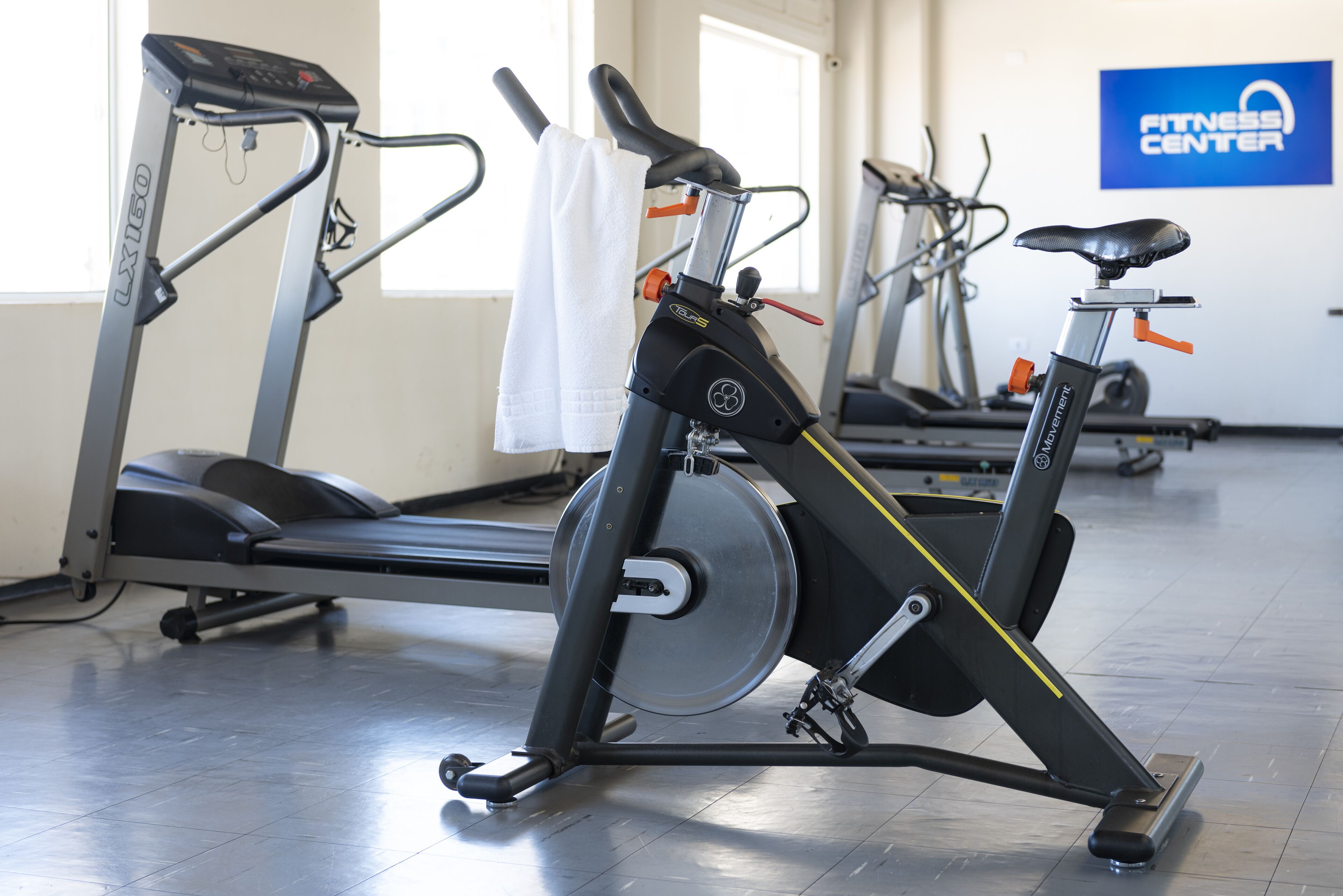 A gym with stationary bikes, treadmills, and a sign reading "Fitness Center".
