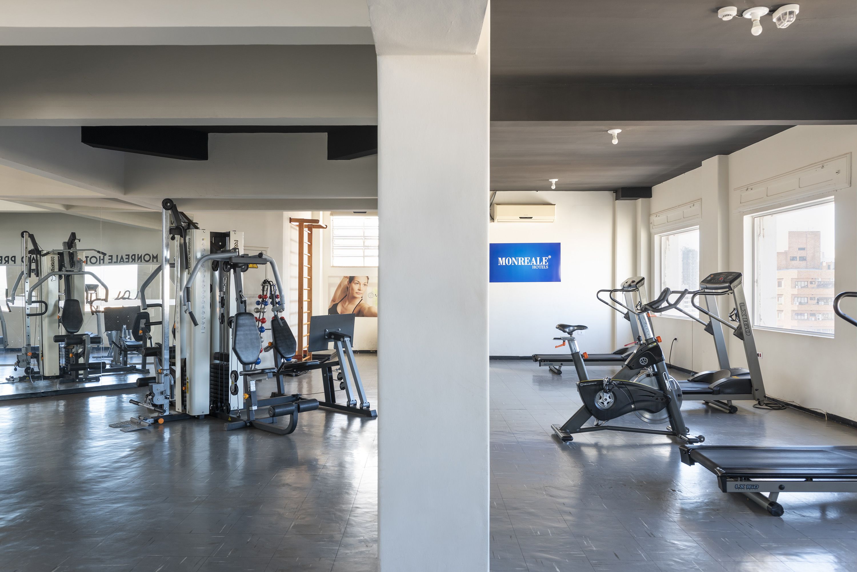 A gym with cardio machines, weight machines, and a mirrored wall.