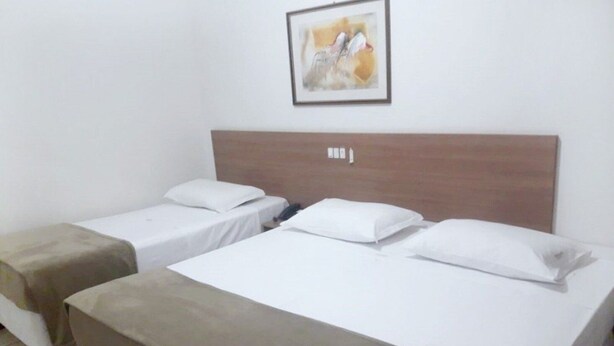 Une chambre d’hôtel avec deux lits simples, une tête de lit en bois et un tableau encadré au mur.