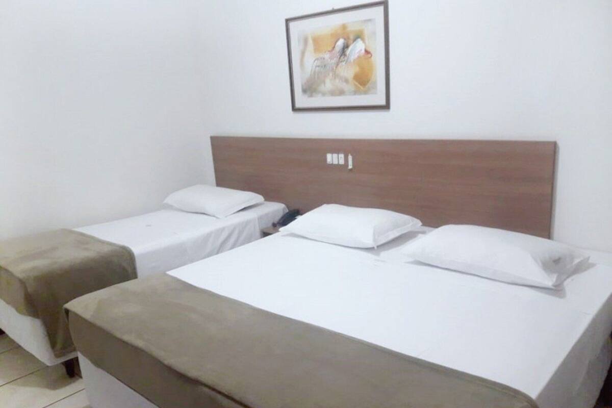 Una habitación de hotel con dos camas individuales, un cabecero de madera y un cuadro enmarcado en la pared.