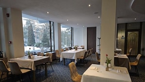 Ein Restaurant mit mehreren Tischen, Stühlen und einem Teppichboden.