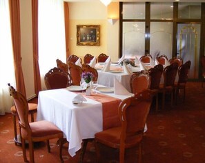 A dining area with multiple tables set for a meal, surrounded by wooden chairs. - Best Western Silva Hotel (Sibiu)