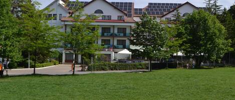 A building with multiple floors, solar panels on the roof, and a well-maintained lawn in front.