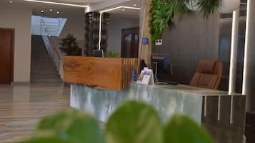 Un mostrador de recepción con encimera de madera, una silla marrón y una planta.