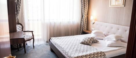 Una habitación de hotel con una cama, un escritorio y una silla.